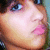 Pixelated close-up of a person's face with light skin, blue eyes, and pink lips, showing partial facial features against a blurred background.