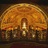 A pixelated image of a golden arch structure with vertical supports and a reflective surface below.