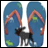 A black dog stands between two blue flip-flops with orange straps, positioned on a white background.