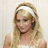 Pixelated static image of a person with light brown hair wearing a white headband and sleeveless top, set against a pale background.