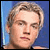 Static pixelated image of a person's face with light brown hair against a blue background, rendered in low-resolution style typical of early 2000s digital art.