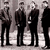 Four figures in dark suits stand side-by-side against a light background with purple text reading "Beatles rock my flaming fuzzy socks off!!!" on the right.
