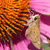 A pixelated image of a light brown owl perched on a branch with orange and brown foliage against a pink background.