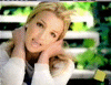 Britney Spears in three distinct poses: resting hands behind head, holding a yellow object, and seated next to a large circular device with two dark circles.