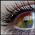 A close-up of a human eye with long dark lashes, green and brown iris hues, and visible eyelid skin showing subtle texture.