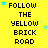 Yellow background with black text reading FOLLOW THE YELLOW BRICK ROAD and scattered blue stars, some of which move across the frame.