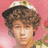 A pixelated image of a person with curly brown hair wearing a white and brown cap, against a pink background with red flowers, with the text "HOTTIE" in red at the bottom right.