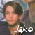 Pixelated portrait of a person with dark hair and light skin, wearing a dark top, with white text reading 'Jake' overlaid at the bottom right.