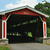 A static pixelated image shows a dark garage with a red roof, white pillars with red stripes, green foliage, and a light blue sky with clouds.