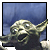 Pixelated image of a small green alien with large ears and eyes, extending one arm against a blue gradient background.