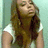 A static image of a person with long brown hair wearing a white sleeveless top against a light blue background.