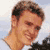 Pixelated static image of a person's head and shoulders with brown hair, light skin tone, and visible facial features against a blurred background.