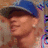 A person wearing a blue cap and light-colored shirt with a patterned background, shown in four with slight head movement
