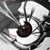 A pixelated close-up of a stylized eye with a dark brown iris, white sclera, and black pupil, set against a grayscale background with abstract shapes.