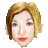 Pixelated portrait of a person with short blonde hair, light skin, and red lips against a gray background.
