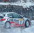 Pixelated static image of a light-colored vehicle with dark wheels and red accents on a blurred background.
