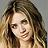 Pixelated static image of a person with long brown hair, light skin tone, and visible facial features including eyes, nose, mouth, and eyebrows.