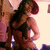 A woman with long dark hair in a black bra and shorts poses against a light background, her head turning from left to right across frames.