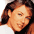 Pixelated close-up of a person's face with brown hair and light skin tone, wearing dark clothing against a white background.