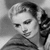 Black-and-white pixelated image of a person with styled hair holding an object near their face, cropped to show upper body and head.