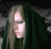 A static image of a person with long light brown hair and blue eyes, wearing dark clothing under a black hooded cloak against a gray textured background.