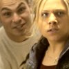Two people in close proximity, one with light hair in a light-colored shirt, the other with long dark hair in a dark jacket over a brown top.