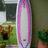 Pixelated image split into two sections: left shows a surfboard with pink and purple borders against a blurred background, right displays purple text on a pink background.