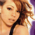 Pixelated close-up of a person with light brown hair and fair skin, wearing a black strap over the shoulder against a gradient background.