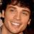 Pixelated close-up of a smiling person with light skin tone, dark hair visible at top and sides, wearing no visible clothing or accessories.