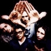 Group of people with hands raised above heads, text overlays changing between 'RESIST', 'Unlearn', and 'Defy!' in a pixelated animation.