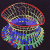 Pixelated abstract shape with layered curved sections in red, blue, green, and brown tones against a dark background.