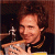 A pixelated image of a person with curly brown hair holding a drumstick near a cymbal, next to green text reading 'Original Icons .com' on a dark background.