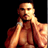 Static pixelated image of a shirtless man with muscular build against black background, wearing white wristband on left arm and dark necklace.