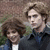 Two people with brown hair stand side-by-side against a blurred background, while pink and yellow text appears on the right.