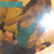 A pixelated image of a person in a teal top and dark pants, with visible text at the top left corner.