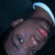 A pixelated image of a person with dark skin, blue eyes, and short hair wearing a white headband against a black background.