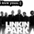 Black-and-white pixelated image showing a group of stylized figures standing behind a large white grid-like structure with dark spots, under a banner reading "Love peace".
