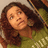 A pixelated close-up of a person with long brown hair wearing a green top, looking slightly upward against a light background.