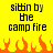 Yellow background with black pixelated text reading 'sittin by the camp fire' and orange pixelated flames at the bottom.