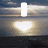 Animated sequence showing a bright light source over water with white shapes changing from vertical bars to heart and then to multiple rounded forms against a cloudy sky background.