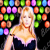 Pixelated image of a person with long blonde hair wearing a dark top with light trim, set against a background of colorful square tiles.