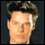 Pixelated static image of a person's head and shoulders with dark hair against a solid background.