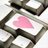 A close-up of a keyboard key with a pink heart symbol on its surface, surrounded by other keys.