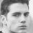 Black-and-white pixelated portrait of a person with short dark hair, closed eyes, and neutral expression against light background.