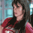 Pixelated static image of a person with dark hair wearing red and black clothing against a blue-gray background.