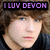 Pixelated image of a person with light skin and brown hair, wearing dark clothing, under purple text reading "I LUV DEVON" on black background.