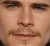 Pixelated close-up of a human face showing eyes, nose, mouth, and partial cheeks with brown hair visible at the bottom edge.