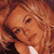 Pixelated close-up of a person with light brown hair and visible facial features including an eye, nose, and mouth against a warm-toned background.