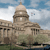 Pixelated image of a domed building with columns under a blue sky with clouds.