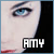 A close-up of a person's eye with blue irises and dark eyeliner, featuring the text 'AMY' in pixelated letters below the eye.